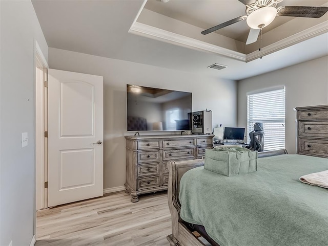 bedroom featuring ceiling fan, a tray ceiling, and light wood-type flooring