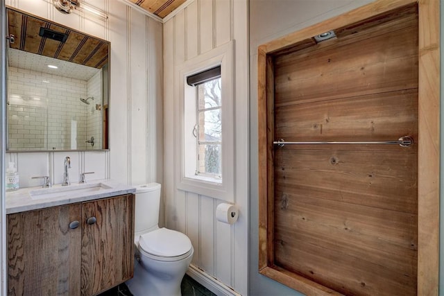 bathroom with toilet, vanity, and wood walls