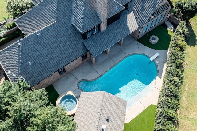 view of pool with a diving board and an in ground hot tub