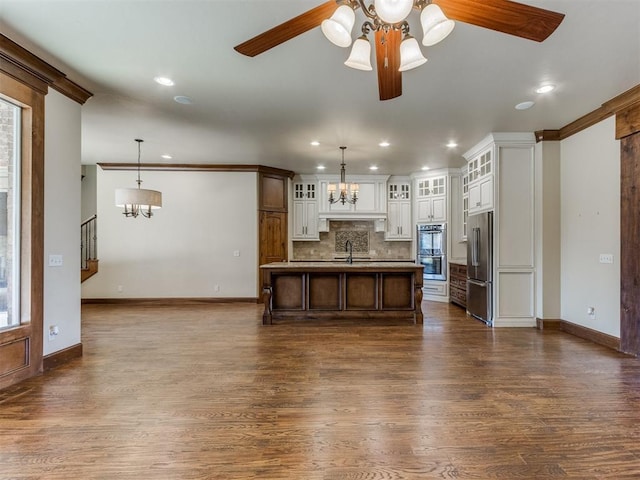 kitchen featuring stainless steel appliances, a kitchen breakfast bar, hanging light fixtures, and a center island with sink