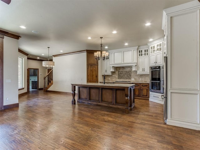 kitchen featuring an inviting chandelier, a breakfast bar, hanging light fixtures, and a center island with sink