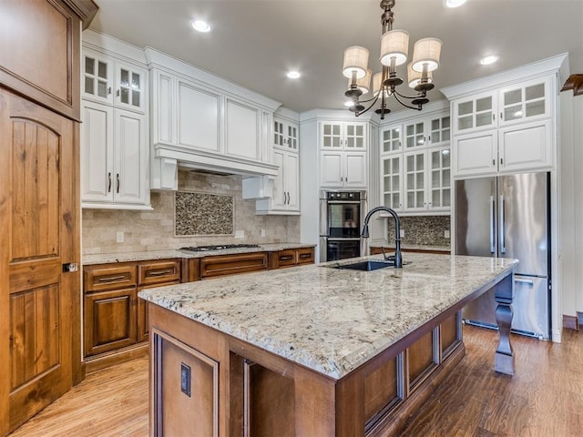 kitchen featuring white cabinetry, a center island with sink, and pendant lighting