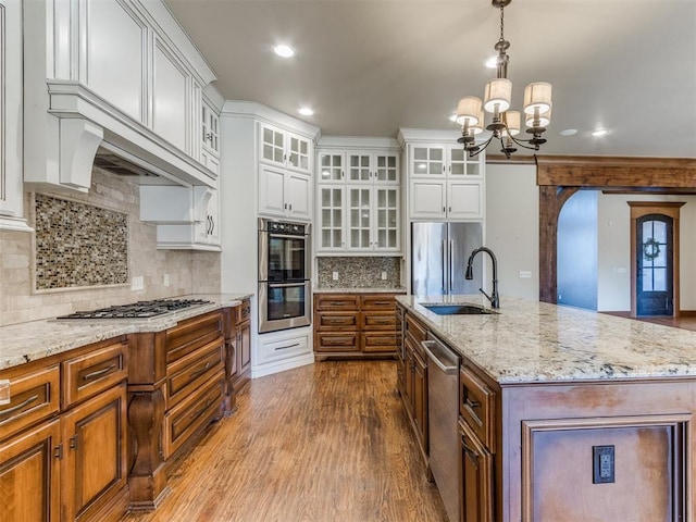 kitchen featuring sink, appliances with stainless steel finishes, white cabinets, and a center island with sink