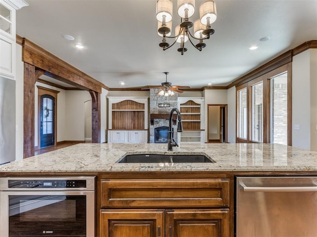 kitchen featuring sink, hanging light fixtures, ornamental molding, stainless steel appliances, and light stone countertops