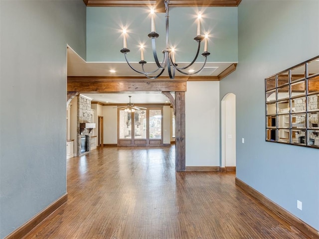 unfurnished living room with crown molding, ceiling fan with notable chandelier, hardwood / wood-style floors, and a high ceiling