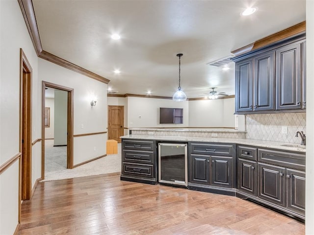 kitchen featuring wine cooler, sink, crown molding, light hardwood / wood-style flooring, and decorative backsplash