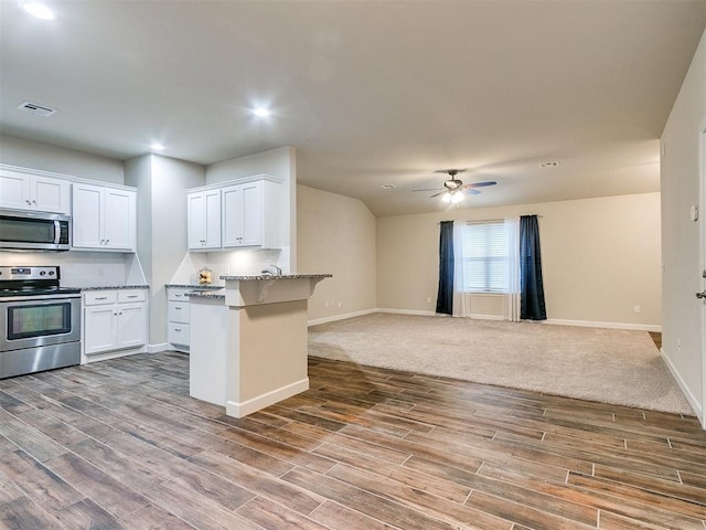 kitchen with light stone counters, wood-type flooring, stainless steel appliances, and white cabinets