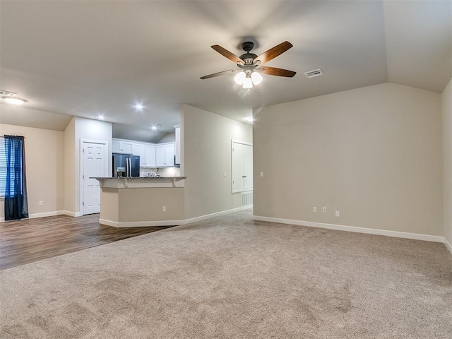 unfurnished living room with ceiling fan, carpet flooring, and vaulted ceiling