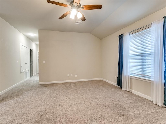 empty room featuring vaulted ceiling, light colored carpet, and ceiling fan