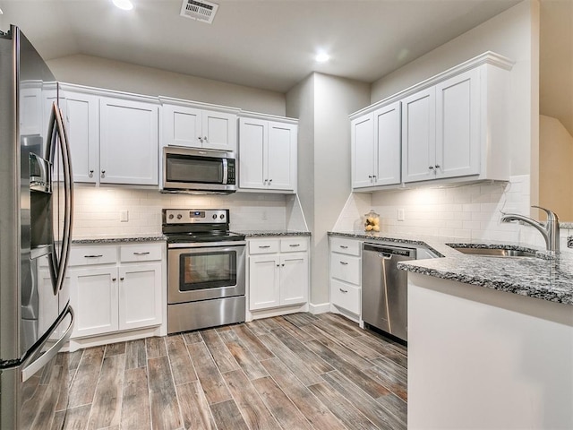 kitchen featuring sink, stainless steel appliances, light stone counters, tasteful backsplash, and white cabinets