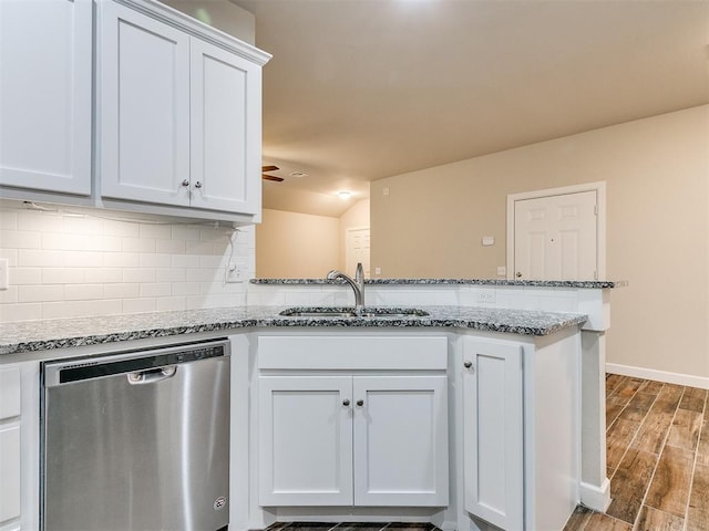 kitchen with light stone counters, sink, white cabinets, and dishwasher