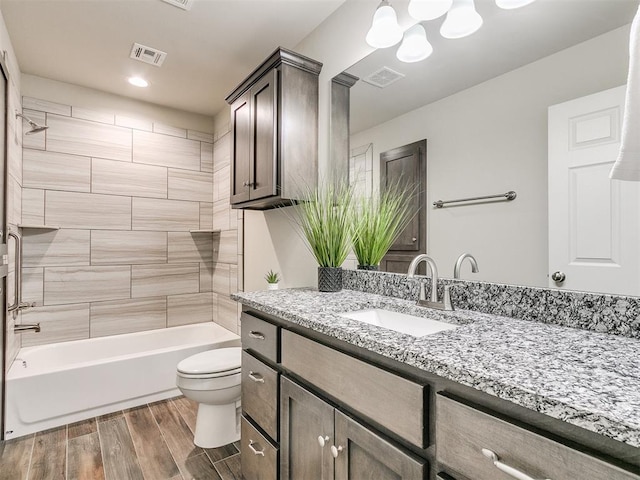 full bathroom featuring hardwood / wood-style flooring, tiled shower / bath, vanity, and toilet