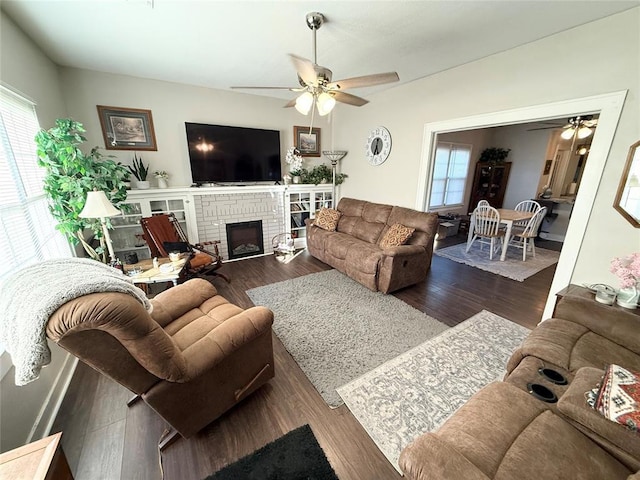 living room with a brick fireplace, dark hardwood / wood-style floors, and ceiling fan