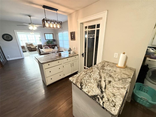 kitchen with washer / clothes dryer, decorative light fixtures, dark wood-type flooring, and kitchen peninsula