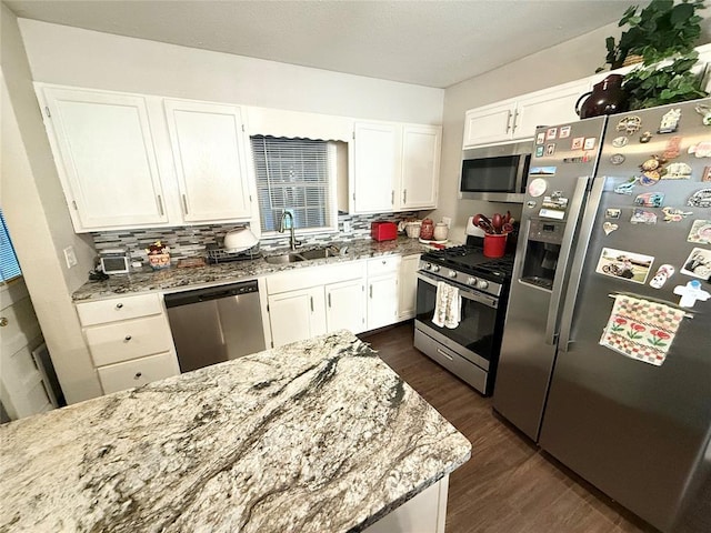 kitchen with stainless steel appliances, light stone countertops, sink, and white cabinets