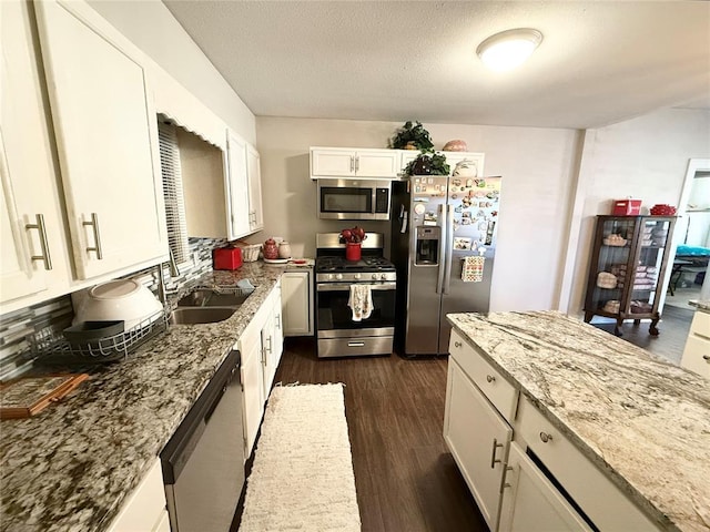 kitchen featuring white cabinetry, sink, dark hardwood / wood-style flooring, stainless steel appliances, and light stone countertops