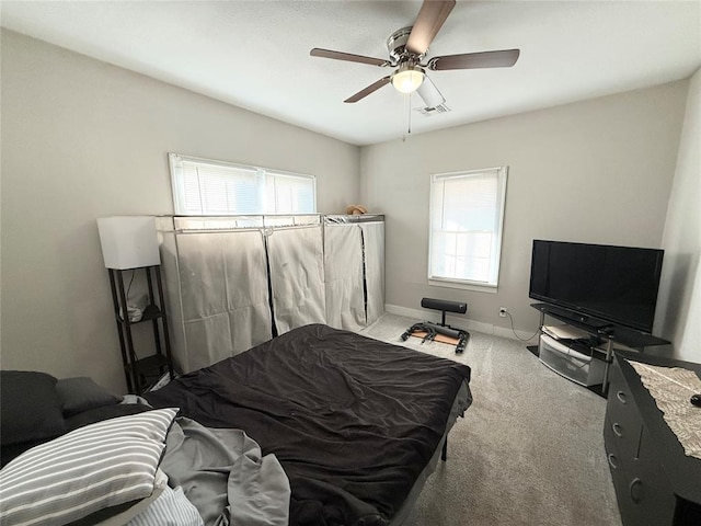 bedroom with ceiling fan, carpet floors, and multiple windows