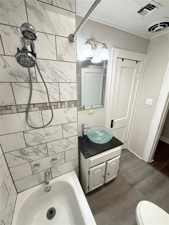 full bathroom featuring hardwood / wood-style flooring, vanity, toilet, and tiled shower / bath combo