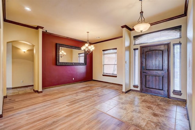 entryway with an inviting chandelier, crown molding, light hardwood / wood-style flooring, and plenty of natural light