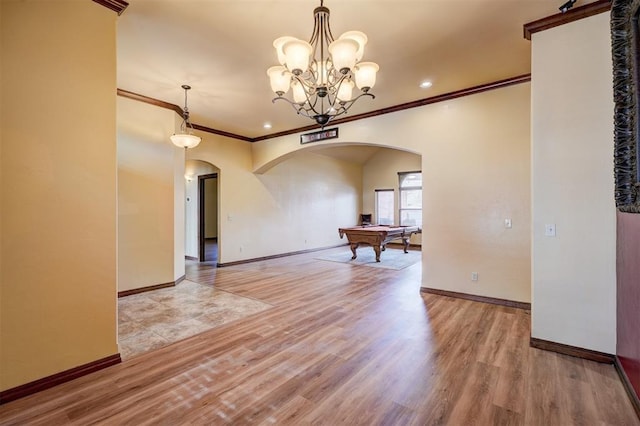 unfurnished dining area featuring a notable chandelier, crown molding, and light wood-type flooring