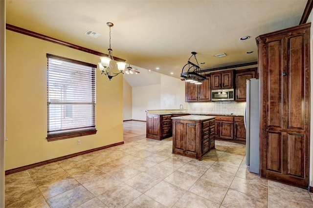 kitchen featuring appliances with stainless steel finishes, a kitchen island, a notable chandelier, pendant lighting, and decorative backsplash