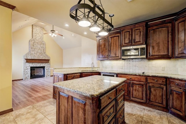 kitchen featuring a kitchen island, pendant lighting, sink, light tile patterned floors, and light stone countertops