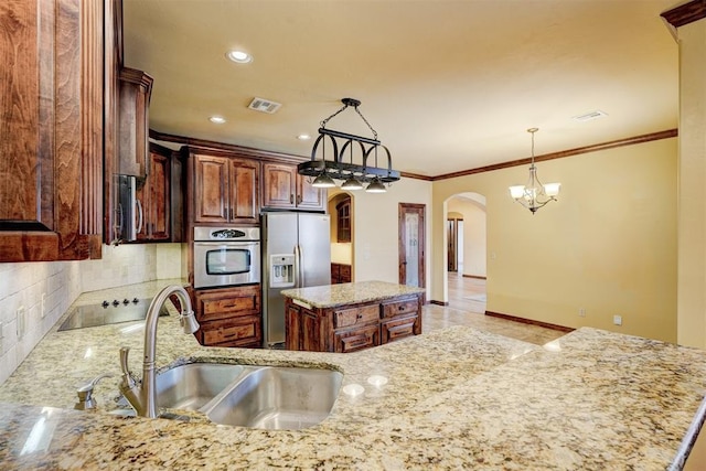 kitchen featuring sink, appliances with stainless steel finishes, hanging light fixtures, a center island, and decorative backsplash