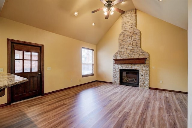 unfurnished living room featuring ceiling fan, high vaulted ceiling, a fireplace, and light hardwood / wood-style floors