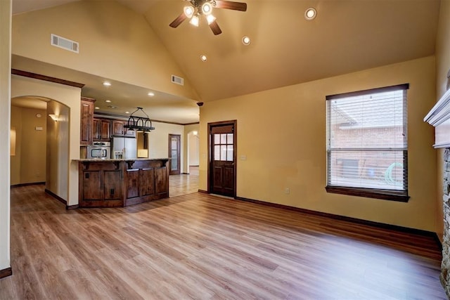 kitchen featuring light hardwood / wood-style flooring, plenty of natural light, kitchen peninsula, and stainless steel refrigerator with ice dispenser