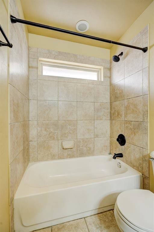 bathroom featuring tile patterned flooring, tiled shower / bath, and toilet