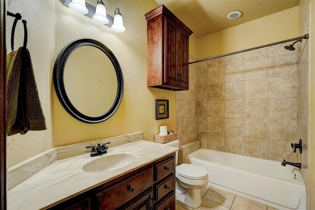 full bathroom featuring tile patterned flooring, vanity, tiled shower / bath, and toilet