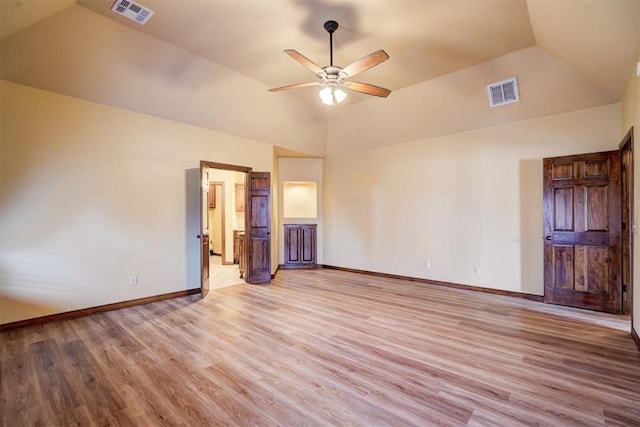 interior space with lofted ceiling, a tray ceiling, ceiling fan, and light wood-type flooring