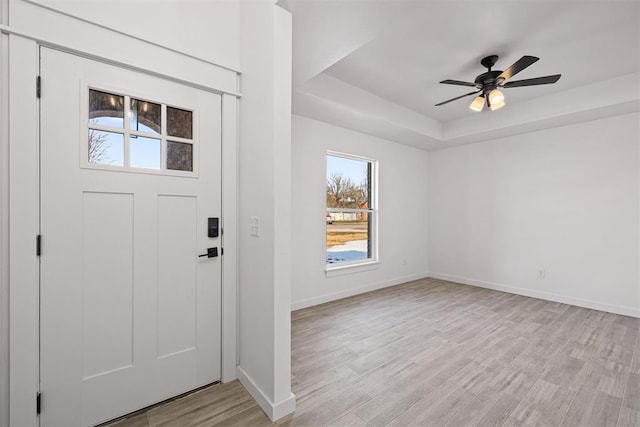 entryway featuring ceiling fan, light hardwood / wood-style flooring, and a tray ceiling