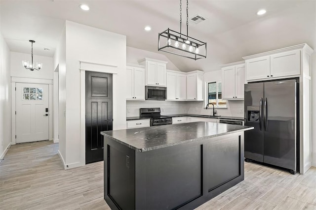 kitchen featuring stainless steel appliances, white cabinetry, hanging light fixtures, and a center island