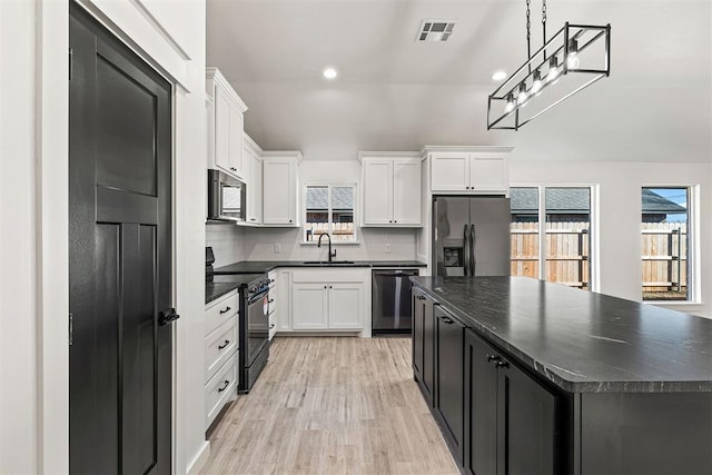 kitchen with black appliances, a center island, white cabinetry, tasteful backsplash, and sink