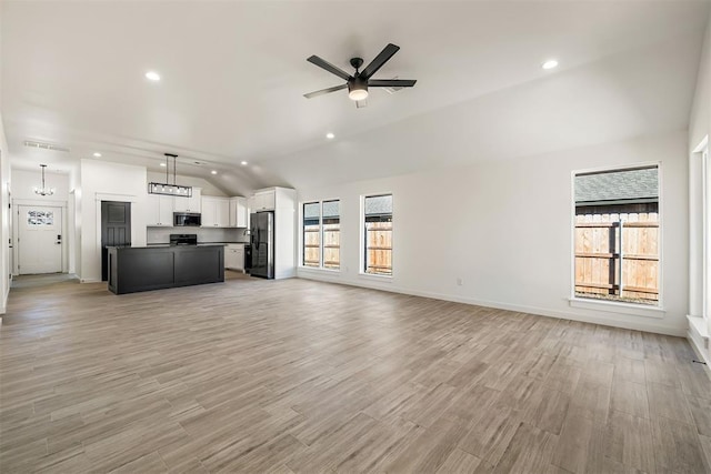 unfurnished living room with lofted ceiling and ceiling fan with notable chandelier