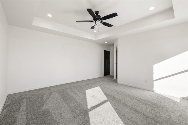 spare room with ceiling fan, carpet flooring, and a tray ceiling