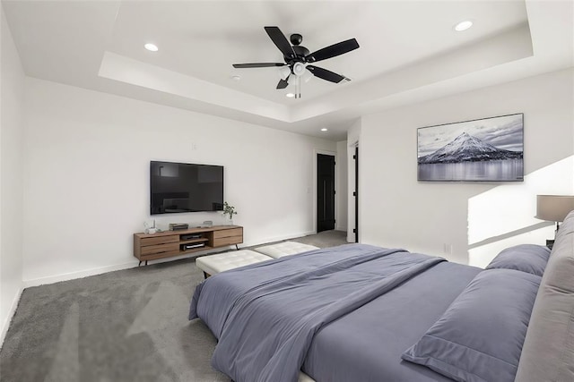 carpeted bedroom featuring a raised ceiling and ceiling fan