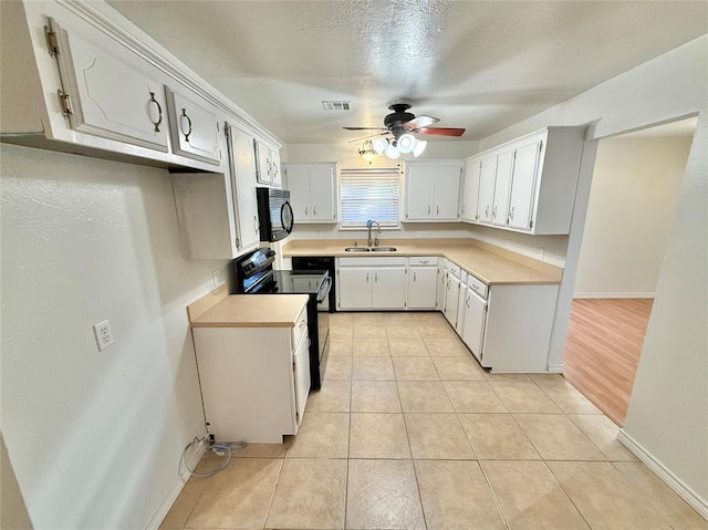 kitchen with light tile patterned flooring, sink, black appliances, ceiling fan, and white cabinets