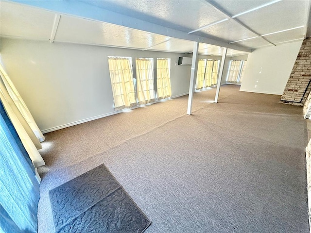 basement featuring a wall mounted air conditioner and carpet flooring