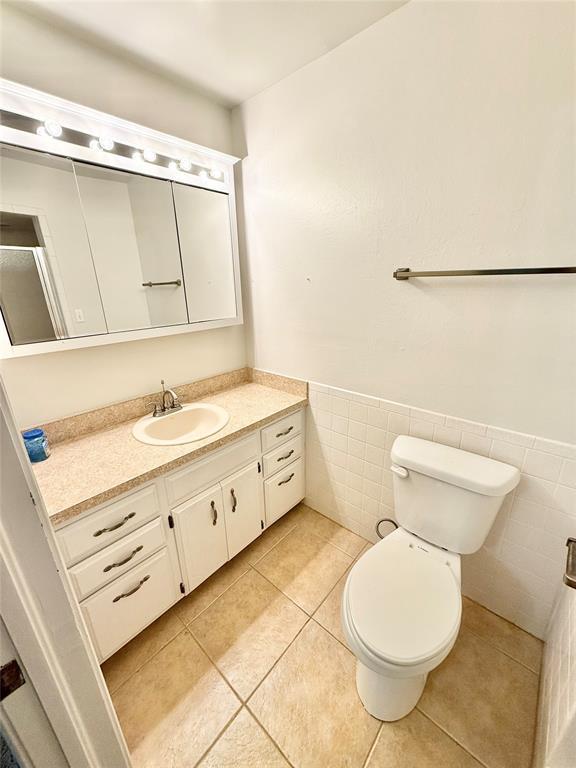 bathroom with vanity, toilet, tile patterned flooring, and tile walls