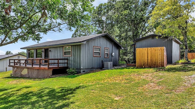 rear view of house featuring central air condition unit, a deck, a storage unit, and a lawn