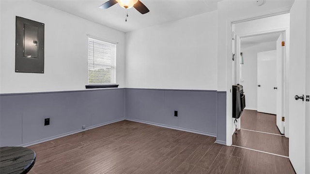 empty room featuring electric panel, ceiling fan, and dark wood-type flooring