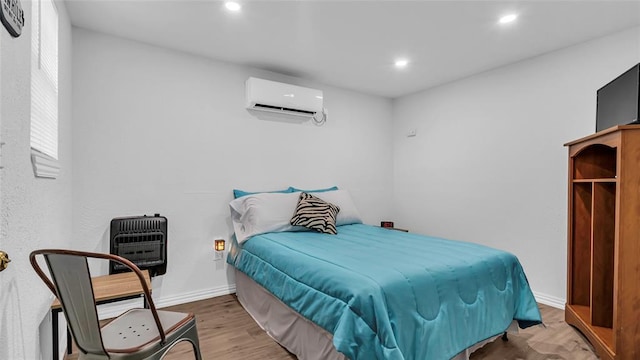 bedroom with an AC wall unit, heating unit, and wood-type flooring