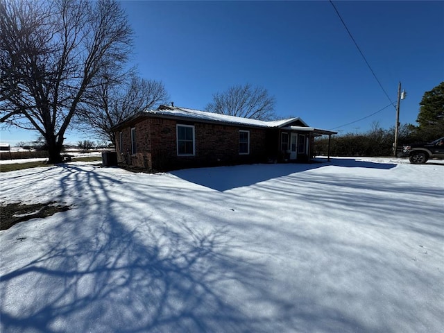 view of snowy exterior with brick siding