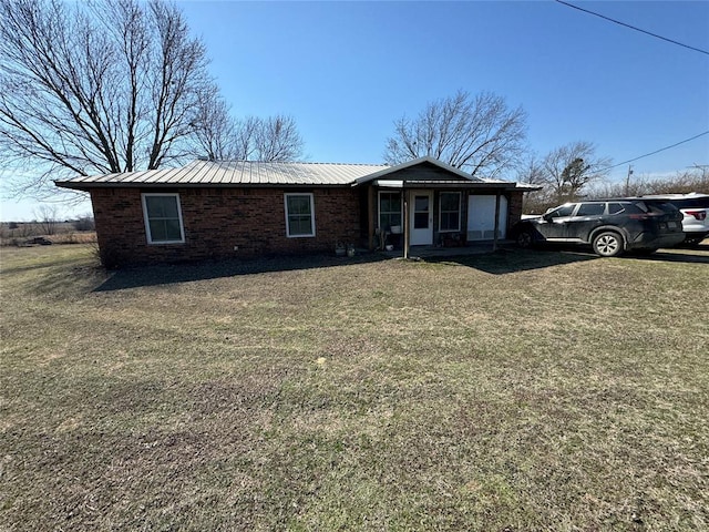 single story home featuring a front yard, brick siding, and metal roof