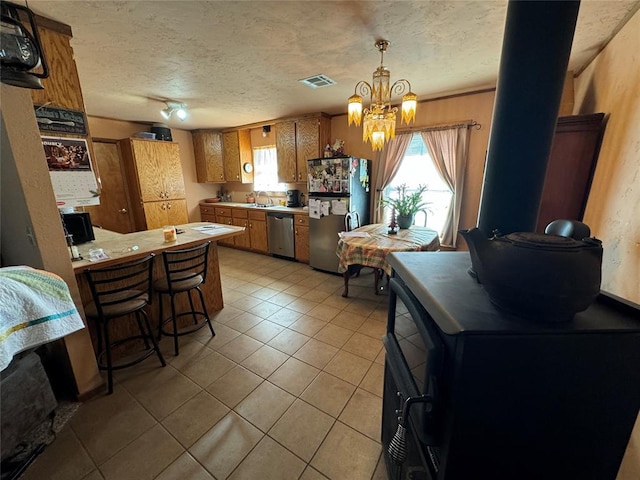 kitchen featuring light tile patterned floors, visible vents, brown cabinetry, stainless steel appliances, and light countertops