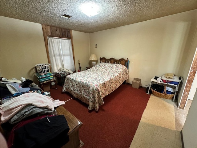 bedroom with a textured ceiling, carpet, and visible vents