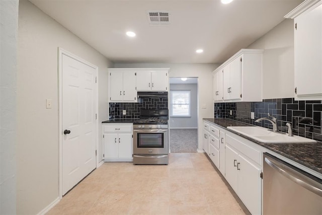 kitchen featuring stainless steel appliances, sink, white cabinets, dark stone countertops, and light tile patterned floors