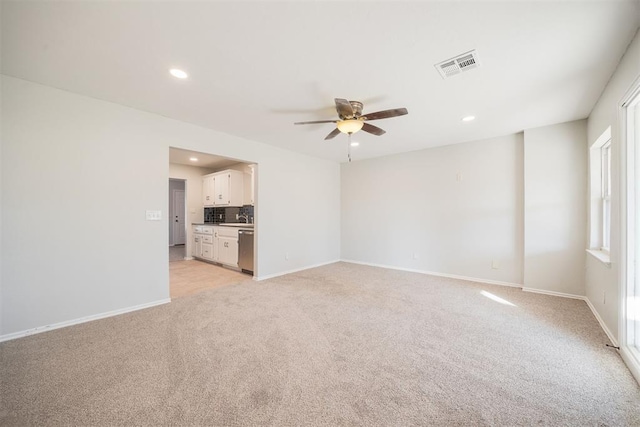 unfurnished living room featuring ceiling fan, light carpet, and sink